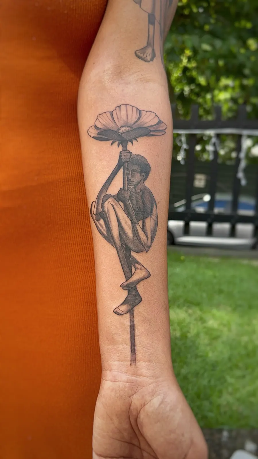 Tatuagem autoral de figura segurando uma flor
